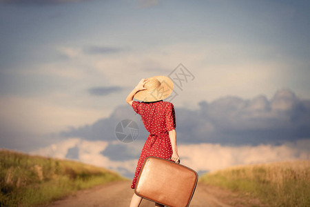 带着包袋在路上行走的年轻红发女孩在农图片
