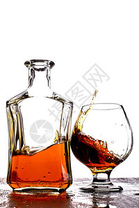一杯泼溅威士忌桌上放着瓶子白色背光背景图片