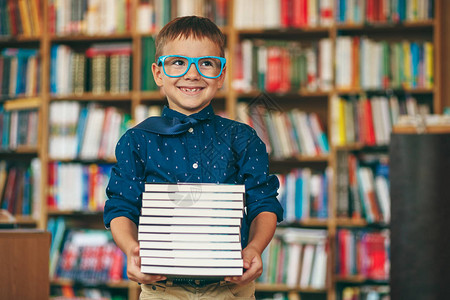 带着蓝色眼镜架和蓝色领带的微笑学生在书本背景上图片