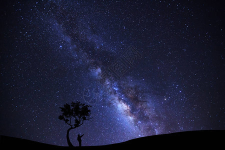 人类正站在一棵树上指着一颗闪亮的恒星银河系和宇宙图片
