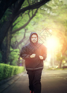 身着在绿公园跑的兜帽衫运动图片