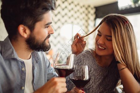 在庆祝情人节或周年纪念时喝着红葡萄酒的一对漂亮的浪漫情图片