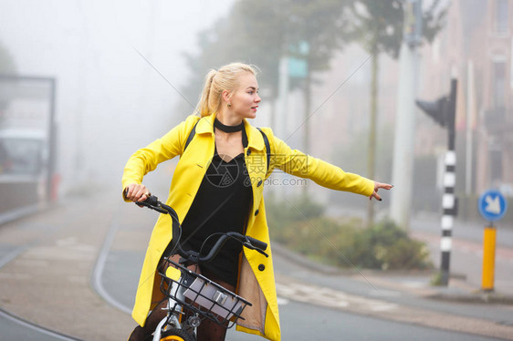 在迷雾城市骑自行车穿着黄外套的图片
