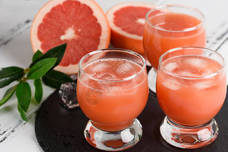 木制背景上的葡萄柚汁和成熟的葡萄柚图片