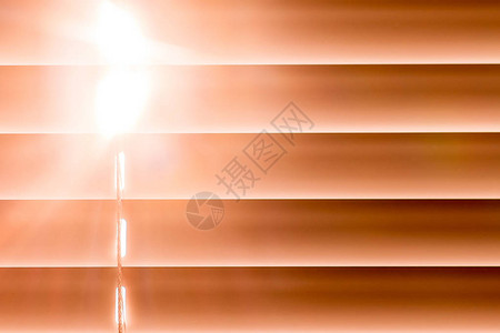 窗口上的橙色水平百叶窗帘通过光线穿透的间隔背景图片