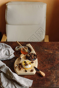 开胃布里干酪配蜂蜜罐和木桌上的核桃图片