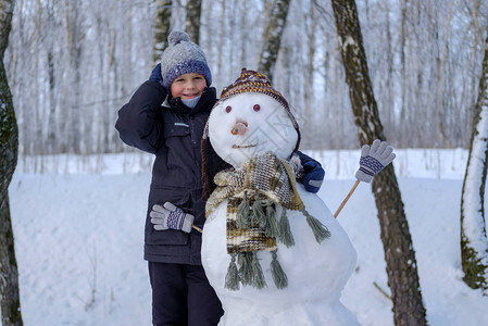 冬日雪地里可爱的欧洲男孩和雪地树林图片