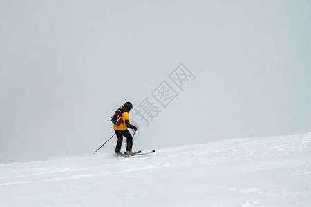 孤单滑雪者与滑雪杆一起在雪山上向前移图片