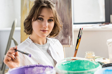 年轻的美术女青年在灯光工作室的油漆中灌图片