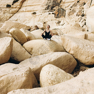 白天在海滨的大岩石山上做瑜伽姿势的放松时图片
