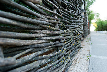 a以石头和绿灌木为背景的铁丝网装饰围栏瓦墙树图片