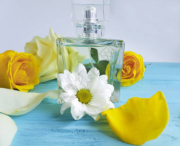 木头上有黄玫瑰的香水瓶背景图片