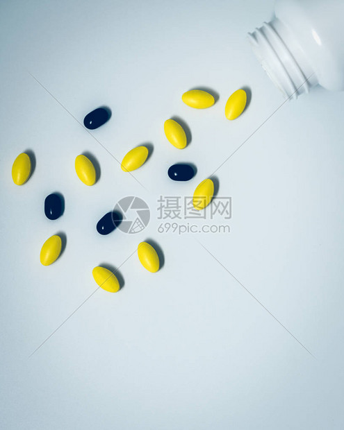 黄色椭圆形药片和黑色药片从药瓶中溢出图片