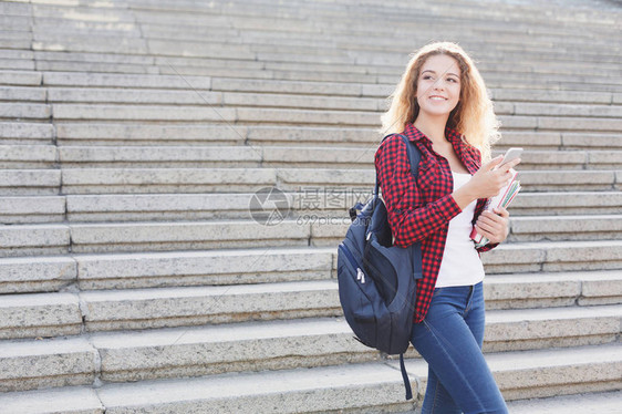 带着笔记本并使用手语的美丽笑容女学生站在大学校园户外休息期间准备参加考试图片