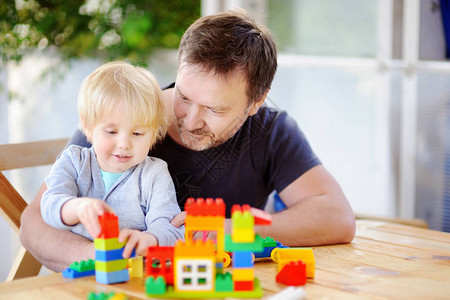 小男孩和他父亲在家玩多彩塑料块游戏图片