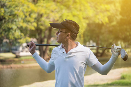 亚洲年轻男高尔夫球手的肖像与高尔夫球场上图片