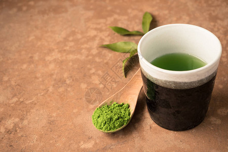 茶杯加绿色茶粉餐桌上的木图片