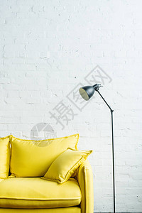 砖墙前的黄色皮沙发和落地灯图片