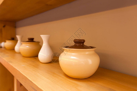 Beige陶瓷锅和白色小花瓶以在木架图片