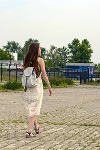 城市中新潮时尚女垂直肖像身着白色吊带裙和皮凉鞋图片