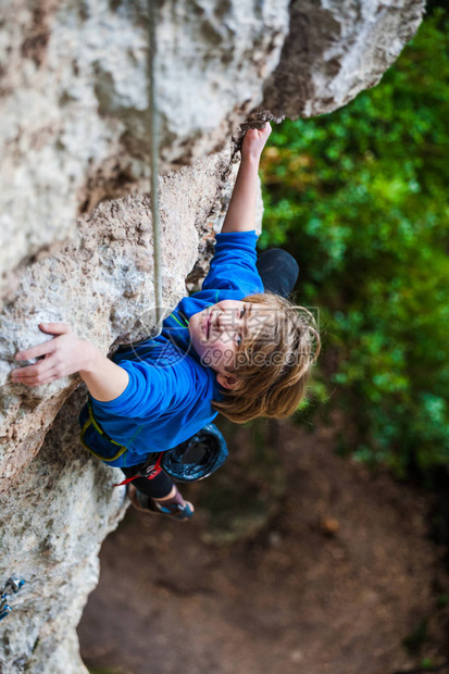 男孩爬上岩石孩子在天然浮雕上进行攀岩运动的孩子积极地花时间在新图片