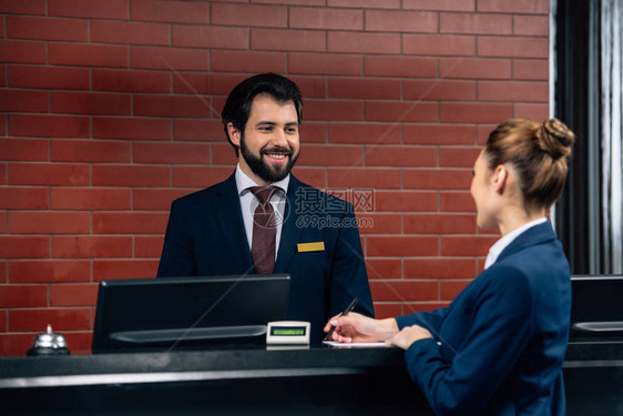 酒店接待员在柜台签合同时与客户交谈图片