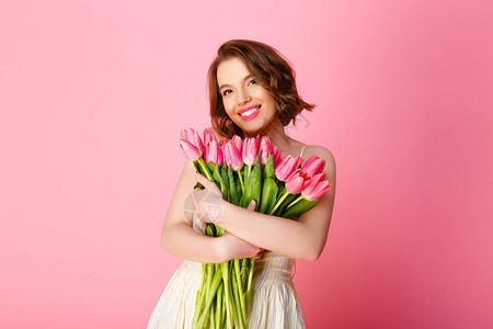 微笑的女人带着一束粉红色的郁金香看着被粉红图片
