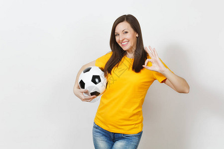 美丽的欧洲年轻女子足球迷或穿着黄色制服的球员拿着足球图片