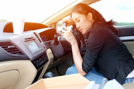 疲倦的年轻女子在她的车里睡着了图片