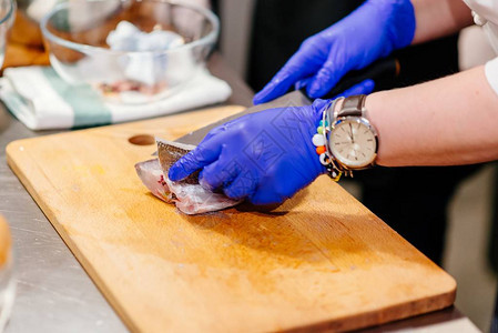 在厨房的木制剪板上用刀子准备和清洗生多拉达鱼图片