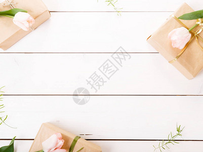 节日花粉红色郁金香组成和白色木制背景上的礼品盒图片