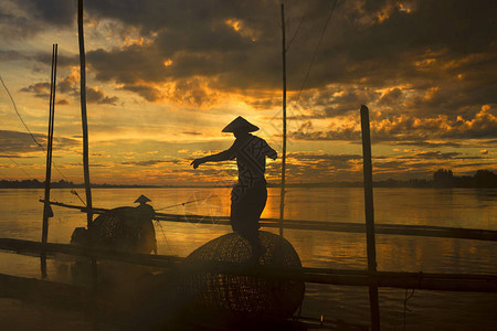 日出时湄公河筏子上渔民的工作图片