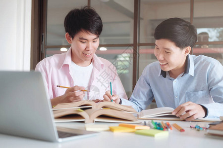 为考试或考试而学习的年轻人与朋友一起辅导书籍年轻学生校园帮助朋友追赶和学习人学习教图片