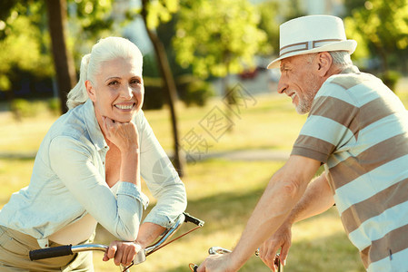 快乐积极的老妇人靠在自行车把上图片