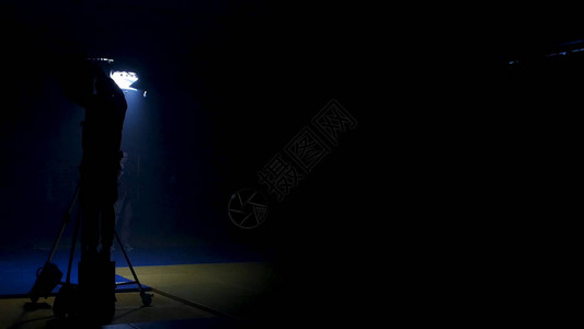 摄制组致力于制作视频灯光师为工作室中的灯光准备扩散加弗将蓝色凝胶涂在视频制作装置上图片