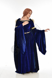 牵小手穿着蓝丝绒中世纪礼服和毛衣的长发妇女全长肖像背景