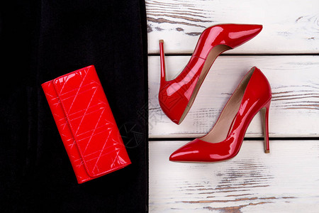 把红鞋和皮夹贴上女人黑衣上的皮带红色钱包明亮的蜜色白背景图片