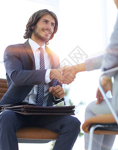 商务握手两个商人在办公室握手背景图片