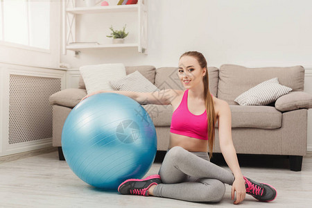 快乐的健身女人在家训练健身球年轻苗条的女孩做有氧运动健康的生活方图片