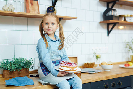 漂亮的小女孩坐在厨房里给客人吃美味的自制蛋糕图片