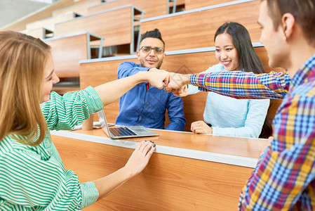 一群在现代大学礼堂结对拳头的欢乐学生图片