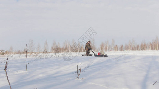 穿冬季衣服的男人快速骑行和驾驶小型雪车在深雪梯图片