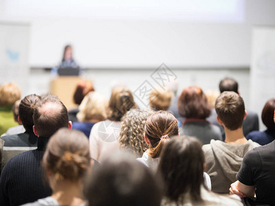 女演讲者在大学讲习班的演讲厅做演讲会议厅内的观众观众中未被识别的参与者的后视图图片