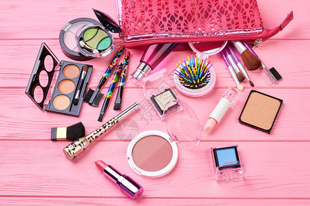 木制背景上的各种化妆产品粉红色木制背景上的装饰化妆品种粉红色的化妆包背景图片