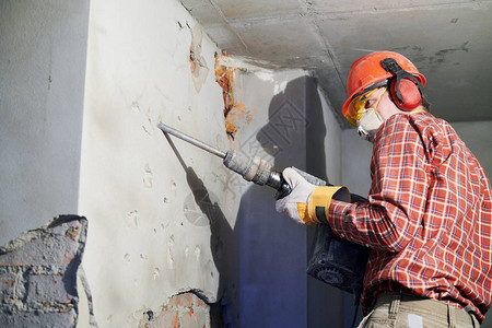 在建筑行业打破内部砖墙施工服务的带有个人防护设备和拆除锤的工人图片