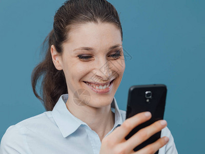 微笑的年轻女与她的智能手机和社交网图片