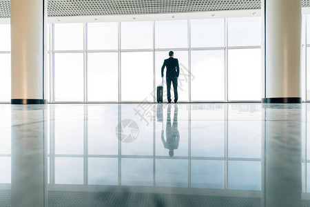 机场的商人拿着手提箱等待门前启程图片