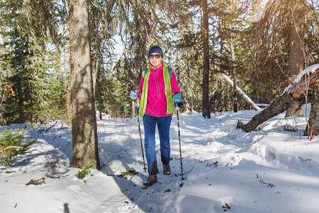 妇女徒步旅行者携带背包和在山区雪迹森林冬季活动和娱乐概念图片