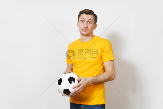 年轻的悲伤沮丧的欧洲男子球迷或身穿黄色制服的球员拿着足球图片