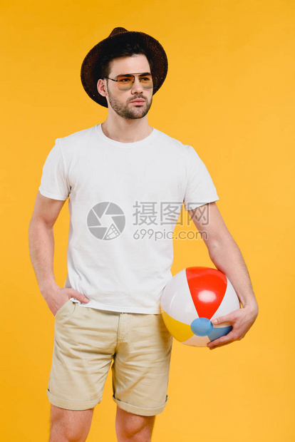 戴着帽子和太阳眼镜的年轻人拿着沙滩球图片